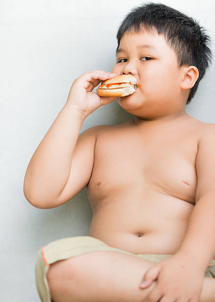 istock obese fat boy child eat chicken hamburger 488086368