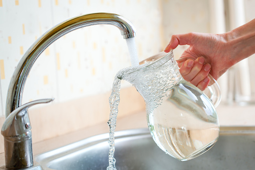 A freelancer businesswoman is taking a break and drinking water in the kitchen.