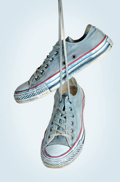 istock Light blue sneakers hanging by the laces against a white background. 488103757