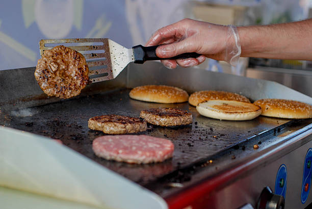 Cooking burgers in a fastfood Cooking burgers in a fastfood restaurant fast food restaurant stock pictures, royalty-free photos & images