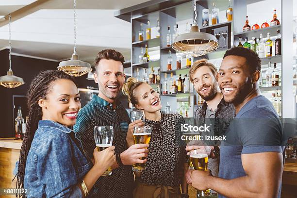 Multi Ethnic Group Of Friends Drinking Beer In A Pub Stock Photo - Download Image Now