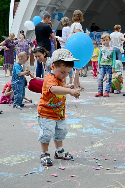 KHARKOV, UKRAINE - 20 JUNE 2015: World Refugee Day observed in Kharkov, Ukraine. A little boy with a blue baloon, playing with colorful pieces of chalk. 