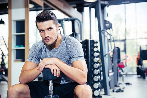 istock Man sitting on the bench with dumbbells at gym 488114996