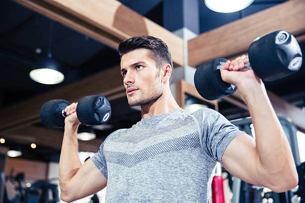 istock Man doing exercises with dumbbells at gym 488115130
