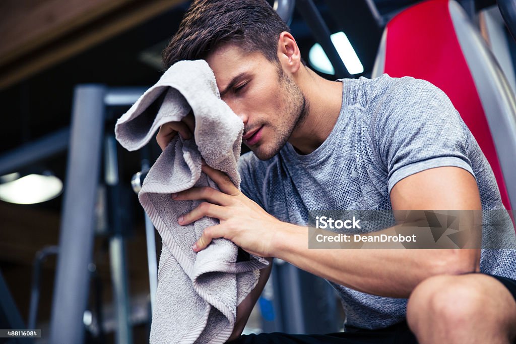 Man sitting on the bench with towel Portrait of a handsome man sitting on the bench with towel in fitness gym Exercising Stock Photo