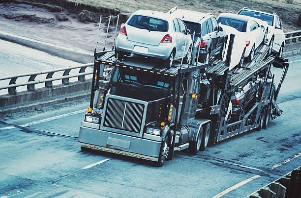 Car Transporter A car transporter straddles the center line of a provincial highway. car transporter photos stock pictures, royalty-free photos & images