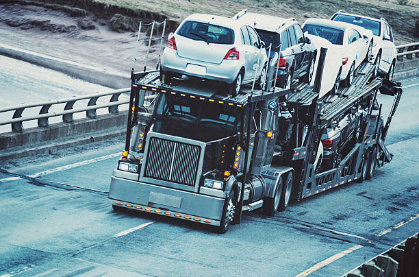 Car Transporter A car transporter straddles the center line of a provincial highway. carrier stock pictures, royalty-free photos & images