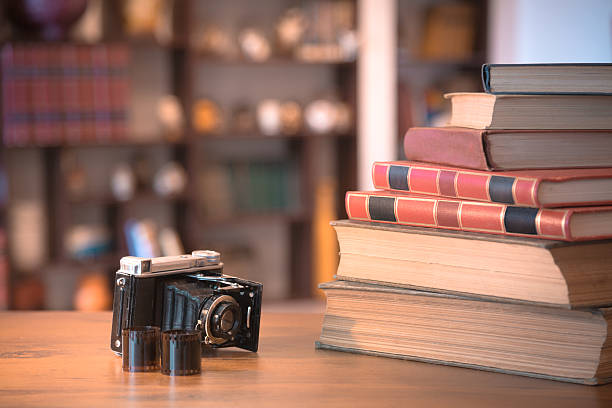 istock Stack of old books and old camera on wooden table 488119582