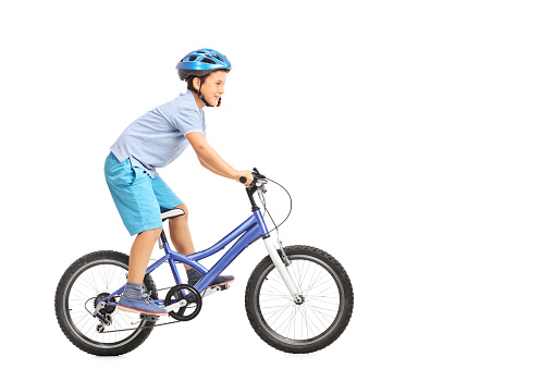Profile shot of a little boy with blue helmet riding a small blue bike isolated on white background