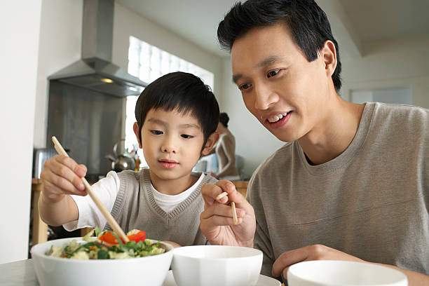 istock Father Watching Son Trying To Use Chopsticks 488124133