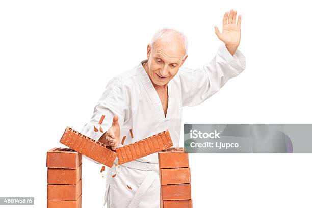 Senior Breaking A Brick With His Bare Hand Stock Photo - Download Image Now - Breaking, Karate, Brick