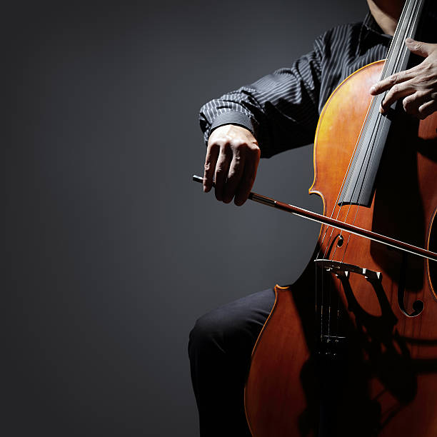 Cello player or cellist performing Cello player or cellist performing in an orchestra isolated with copy space symphony orchestra photos stock pictures, royalty-free photos & images