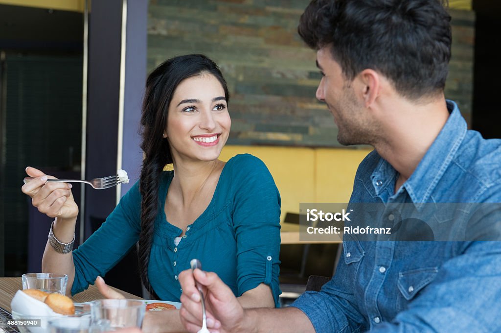 Happy couple having meal Closeup shot of young woman and man in casual having meal. Loving couple looking at eachother during the lunch. Happy smiling couple having lunch at restaurant. Lunch Break Stock Photo