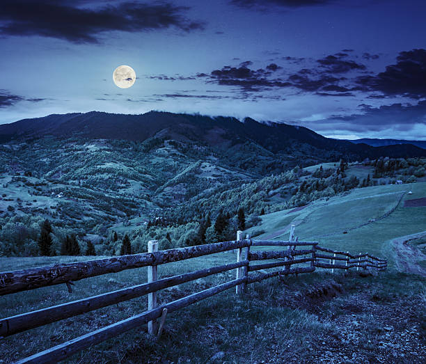 istock fence on hillside meadow in mountain at night 488151720