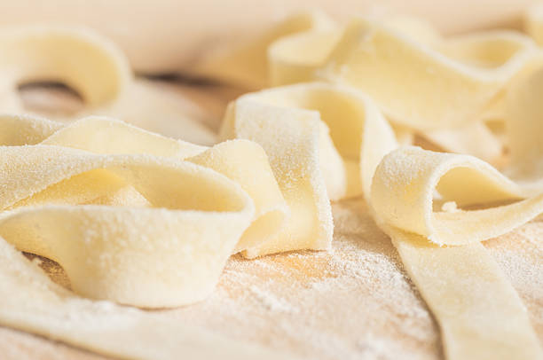 istock Fettuccini pasta dough in flour with a rolling pin 488152204