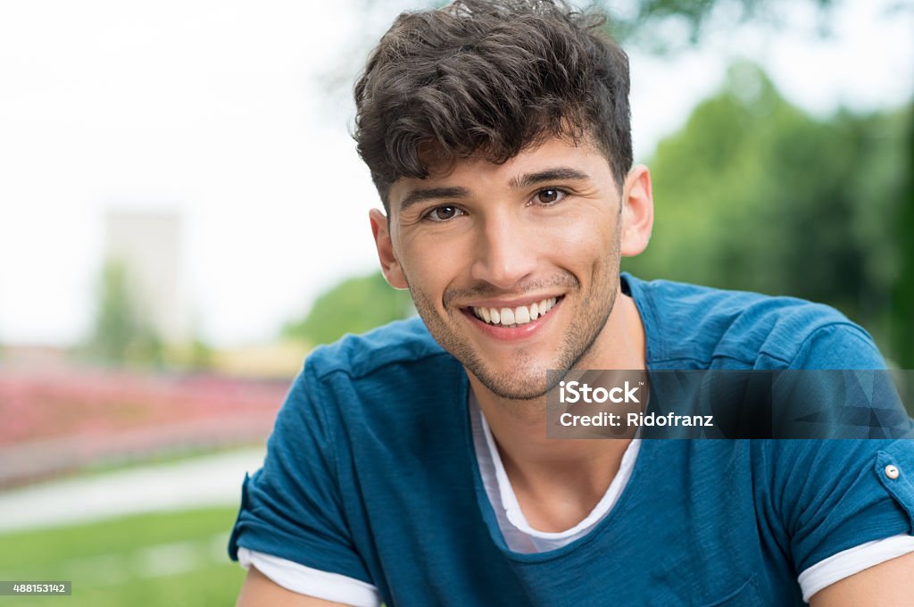 Happy guy Closeup shot of young man looking at camera. Portrait of smiling guy in casual posing outdoor. Smiling teenwith blue tshirt looking at camera at the pak. Teenager Stock Photo