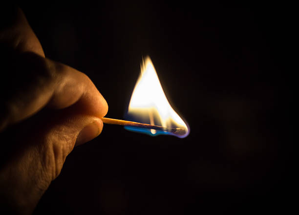 Burning matchstick against black background stock photo