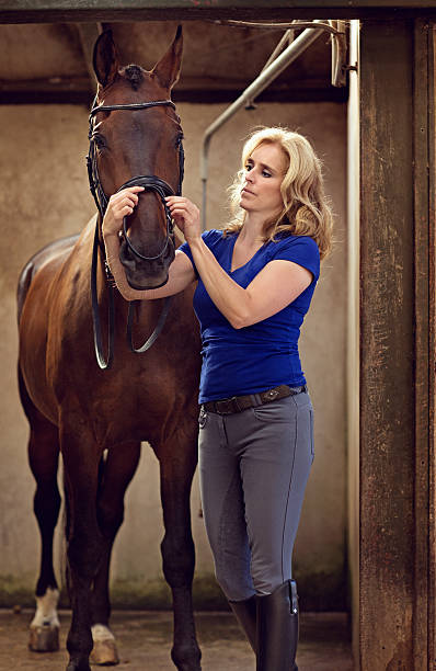 istock woman preparing horse for the ride 488153462