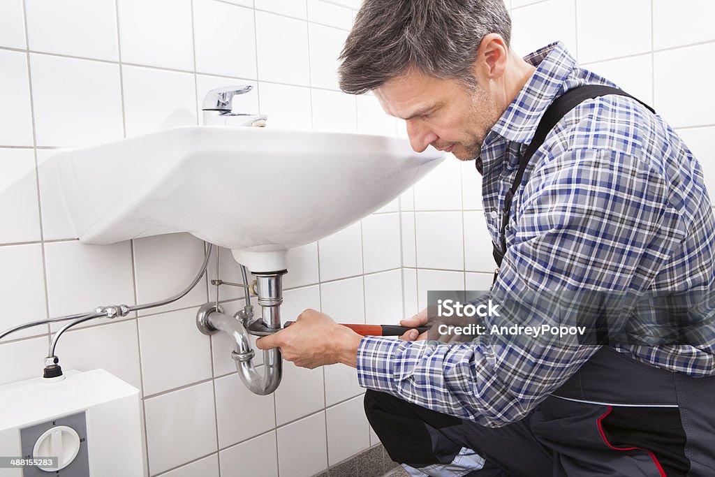 Plumber Fitting Sink Pipe Mature Male Plumber Fitting Sink Pipe In Bathroom Plumber Stock Photo