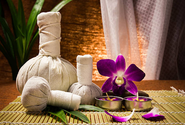 spa de ervas comprimidos bola com velas e orquídea - ayurveda massaging spa treatment wellbeing - fotografias e filmes do acervo