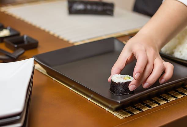 istock Woman chef placing japanese sushi rolls on a tray 488178513