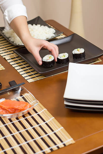 istock Woman chef placing japanese sushi rolls on a tray 488178517