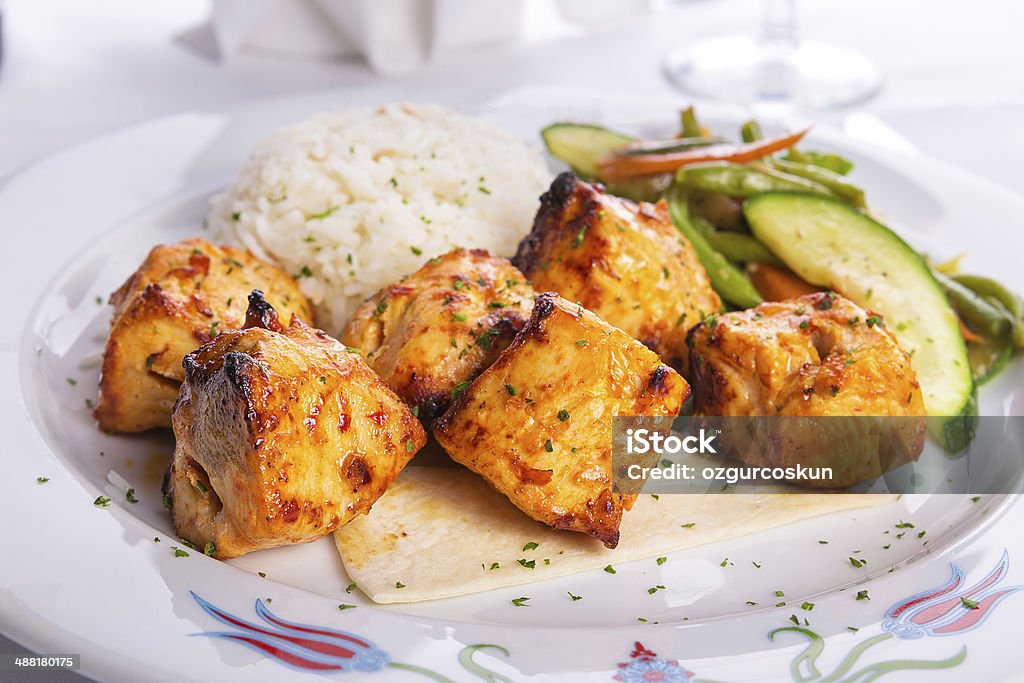 Zesty Chicken Shish Kebabs served on a Lavash Bread Zesty chicken shish kebabs served with rice pilaf on a tiny lavash bread garnished with cooked vegetables zucchini, green beans and carrots Chicken - Bird Stock Photo