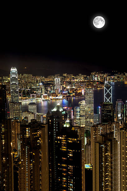 Full Moon Over Victoria Harbor at Night, Hong Kong Full moon overlooking Victoria Harbor atop Victoria Peak in Hong Kong. Vertical Orientation with copy space. hong kong moon night stock pictures, royalty-free photos & images