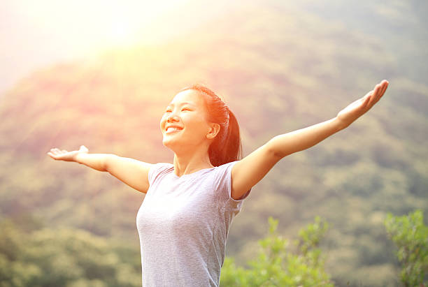 cheering woman open arms at mountain peak