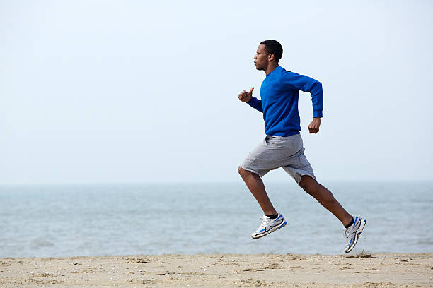 istock Young athletic man running at the beach 488202663