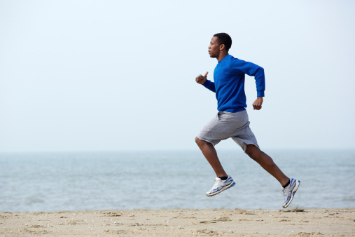 Healthy young athletic man running at the beach