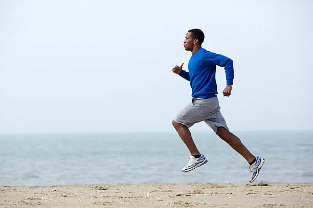 Photo of Young athletic man running at the beach