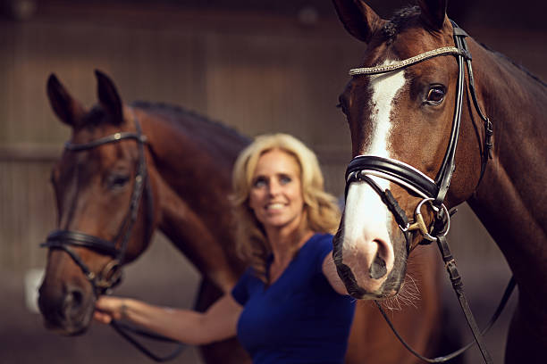 istock woman holding two horses 488208062