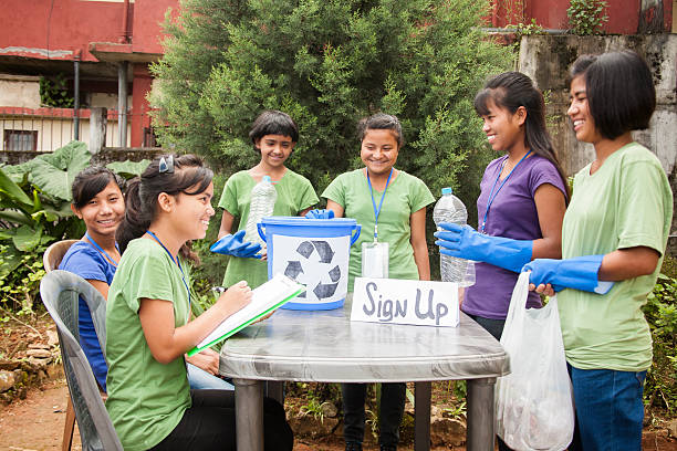 Teenagers register at recycling volunteer check-in table. Multi-ethnic group.