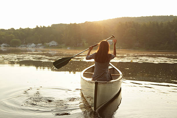 istock Young girl paddling a canoe as the sun rises 488209694