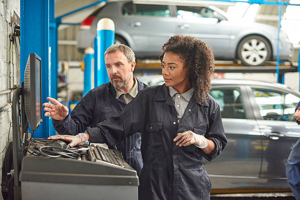 kobieta mechanik samochodowy ze swoim szefem - trainee auto repair shop computer manual worker zdjęcia i obrazy z banku zdjęć