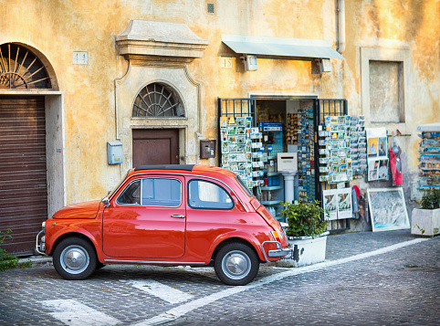 Rome, Italy-April 3, 2013: Red Fiat 500 parked in front of a souvenir shop.