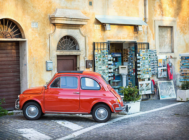Red Fiat 500 parked in front of a souvenir shop. Rome, Italy-April 3, 2013: Red Fiat 500 parked in front of a souvenir shop. little fiat car stock pictures, royalty-free photos & images