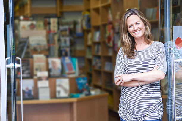 Portrait Of Female Bookshop Owner Outside Store Portrait Of Female Bookshop Owner Outside Store bookstore stock pictures, royalty-free photos & images