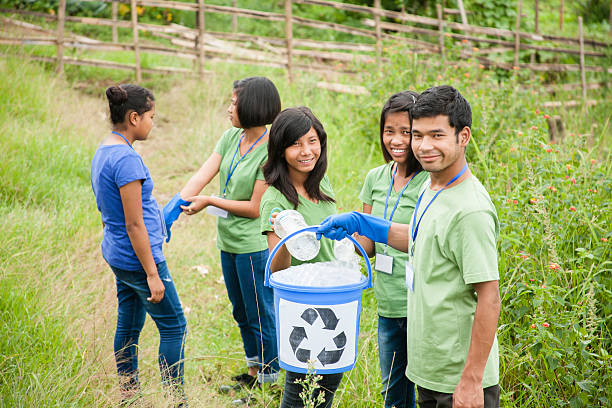 istock Teenage friends picking up trash to recycle. Park setting. 488212640