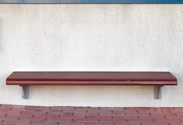 Wooden street bench mounted on white stone wall on bus stop