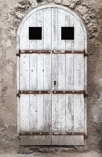 istock Old white wooden door with arch in stone wall 488213400