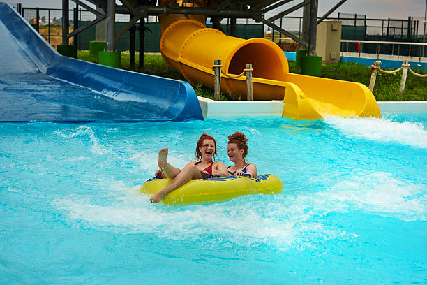 fun moment in aqua park two friends laughing and having fun in inflatable ring in swimming pool, summer concept in water amusement park. holiday camp stock pictures, royalty-free photos & images