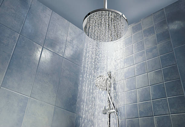 Shower head with running water Low angle of running water from shower head in a cool coloured shower falling water flowing water stock pictures, royalty-free photos & images