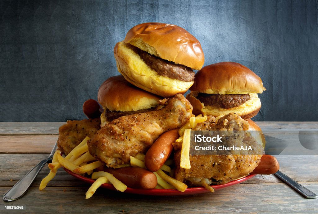 Junk food diet Huge portion of junk food on a plate including burgers, fries, chicken and hot dogs Large Stock Photo