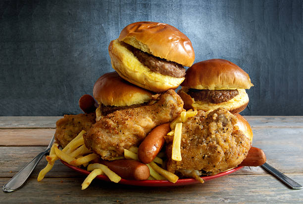 Junk food diet Huge portion of junk food on a plate including burgers, fries, chicken and hot dogs big plate of food stock pictures, royalty-free photos & images