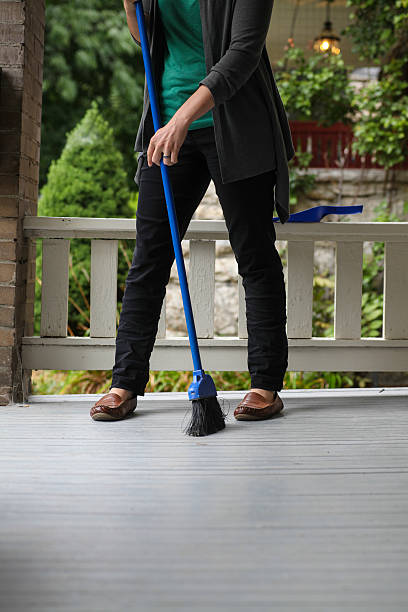 woman sweeps dirt off front porch stock photo