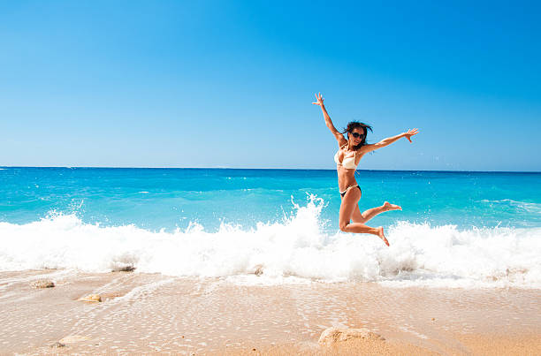 Cute brunette woman jump at sea stock photo