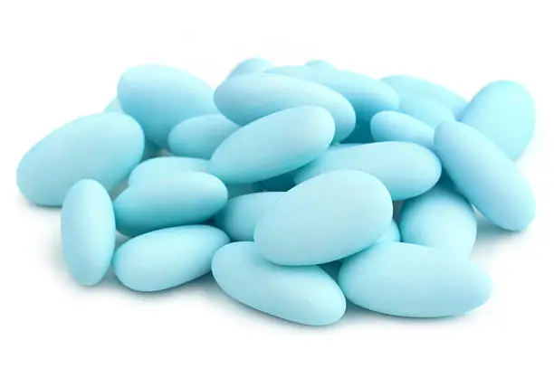 heap of  blue sugared almonds on white background