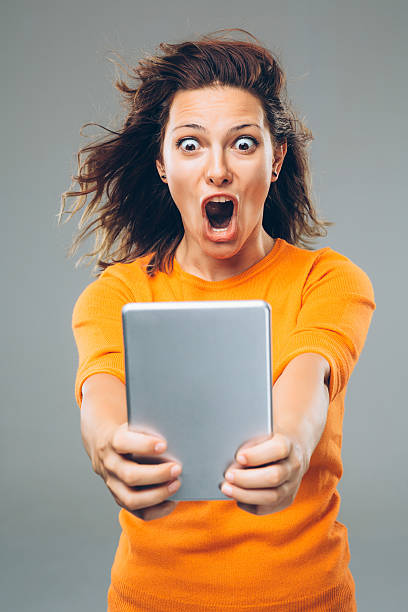 Fast Internet A girl holding a tablet amazed by her powerful internet. mouth open human face shouting screaming stock pictures, royalty-free photos & images